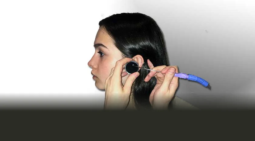 An audiologist removing ear wax from a young woman's ear by microsuction